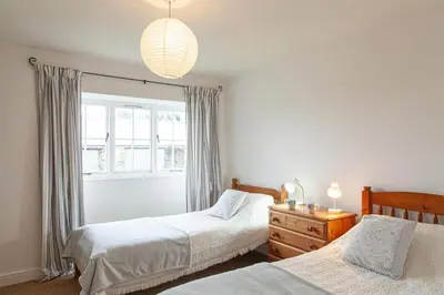 a bedroom with two beds and a window at Carneggan Barn Lanteglos has breath taking views in Lanteglos