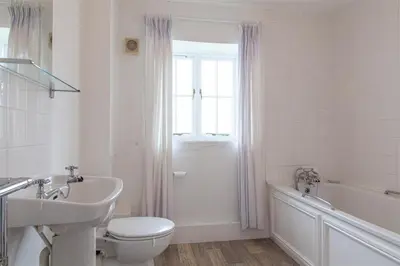 a white bathroom with a toilet and a tub and a sink at Carneggan Barn Lanteglos has breath taking views in Lanteglos