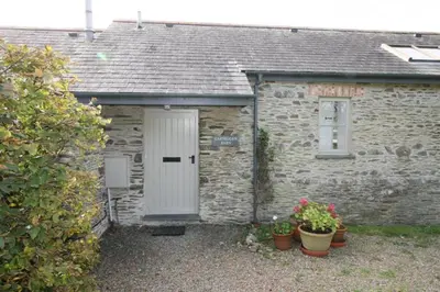 a stone house with a white door and some plants at Carneggan Barn Lanteglos has breath taking views in Lanteglos