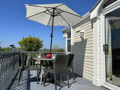 a table and chairs with an umbrella on a balcony at Sunshine Retreat Wadebridge in Wadebridge