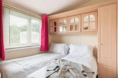 a bedroom with a bed with white sheets and a window at Sunshine Retreat Wadebridge in Wadebridge
