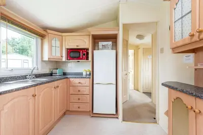 a kitchen with wooden cabinets and a white refrigerator at Sunshine Retreat Wadebridge in Wadebridge