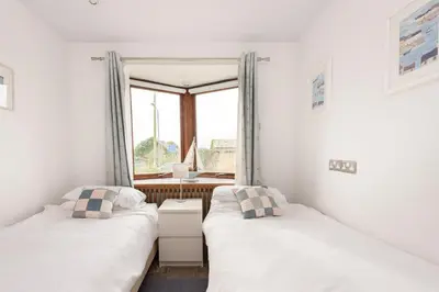 two beds in a room with a window at Cormorants Polruan village sea coastline views in Fowey