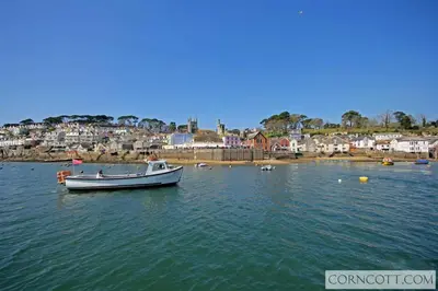 a boat in the water with a town in the background at Cormorants Polruan village sea coastline views in Fowey