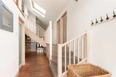 a hallway of a home with white walls and wooden stairs at Cormorants Polruan village sea coastline views in Fowey