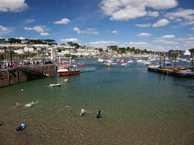 a group of people in the water at a marina at Cuckoo Tor Lanteglos woodland coastline nearby in Lanteglos