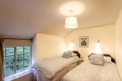 two beds in a room with a window at Cuckoo Tor Lanteglos woodland coastline nearby in Lanteglos