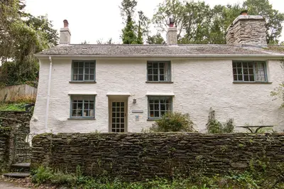 an old white house behind a stone wall at Cuckoo Tor Lanteglos woodland coastline nearby in Lanteglos