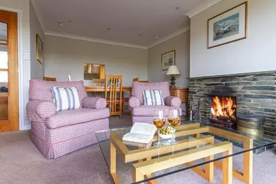 a living room with two chairs and a fireplace at Silvershell lovely views across Port Isaac in Port Isaac