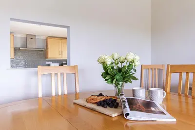a dining room table with a vase of flowers and fruit at Silvershell lovely views across Port Isaac in Port Isaac