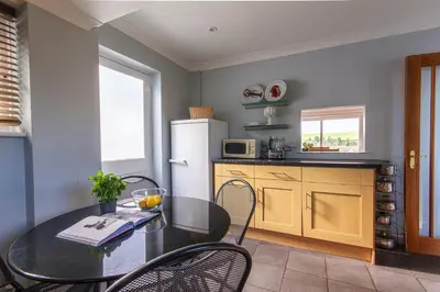 a kitchen with a table and a refrigerator at Silvershell lovely views across Port Isaac in Port Isaac