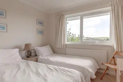 a bedroom with two beds and a window at Silvershell lovely views across Port Isaac in Port Isaac