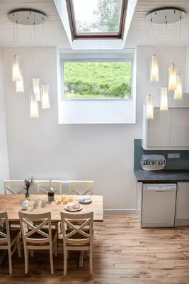 a kitchen with a wooden table and chairs and a window at Organ Loft North Coast moorland on the doorstep in Saint Breward