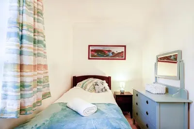 a small bedroom with a bed and a dresser and a mirror at Organ Loft North Coast moorland on the doorstep in Saint Breward