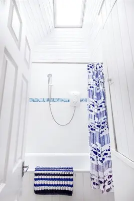 a bathroom with a shower with a blue and white shower curtain at Organ Loft North Coast moorland on the doorstep in Saint Breward
