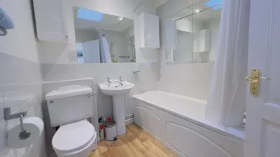 a white bathroom with a toilet and a sink at Seamist Rock - on the north coast of Cornwall in Roche