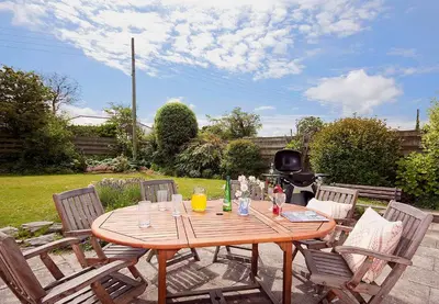 a wooden table and chairs in a yard at Seamist Rock - on the north coast of Cornwall in Roche