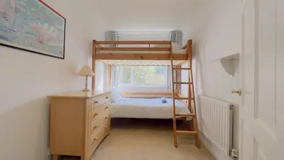 a small bedroom with a bunk bed and a dresser at Seamist Rock - on the north coast of Cornwall in Roche