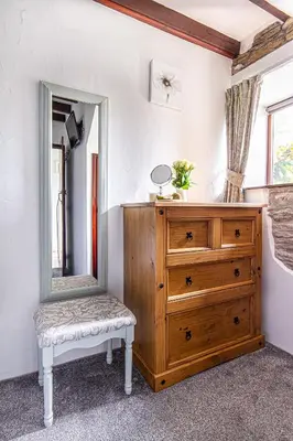 a bedroom with a dresser and a mirror at Rowan Cottage - sleeps 2 - Nr Looe and Polperro in Lanreath