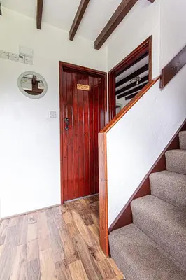 a hallway with a red door and stairs in a house at Rowan Cottage - sleeps 2 - Nr Looe and Polperro in Lanreath