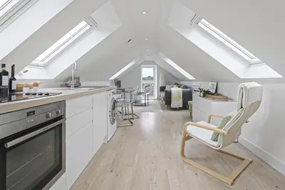 a kitchen with white cabinets and chairs in a room at The Loft in Wadebridge