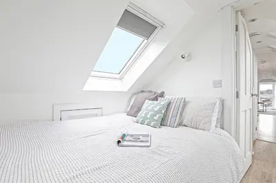 a white bedroom with a bed with a book on it at The Loft in Wadebridge