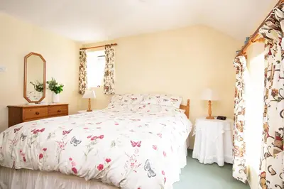 a bedroom with a bed with a floral bedspread at Thumbelina far reaching views of the countryside in Budock Water