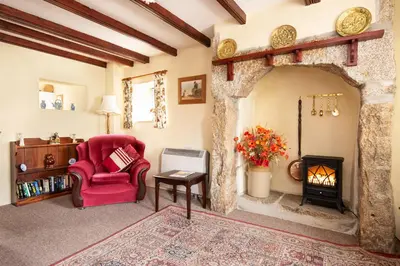 a living room with a red chair and a fireplace at Thumbelina far reaching views of the countryside in Budock Water