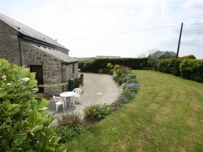 a garden with two chairs and a table and a building at Thumbelina far reaching views of the countryside in Budock Water