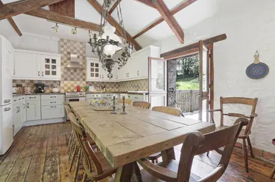 a large kitchen with a wooden table and chairs at The Barn in Camelford
