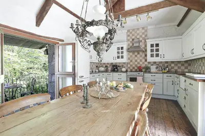 a kitchen with a wooden table with chairs and a chandelier at The Barn in Camelford