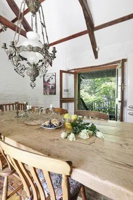 a dining room with a wooden table and a chandelier at The Barn in Camelford