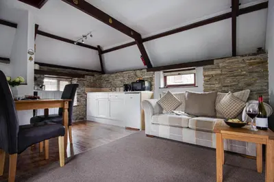 a living room with a couch and a kitchen at Rowan Retreat - sleeps 2 - Nr Looe and Polperro in Lanreath