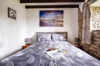 a bedroom with a bed and a picture of a pier at Rowan Retreat - sleeps 2 - Nr Looe and Polperro in Lanreath