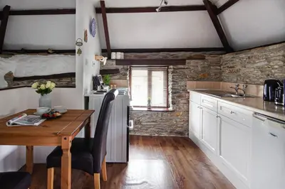 a kitchen with a wooden table and a kitchen with white cabinets at Rowan Retreat - sleeps 2 - Nr Looe and Polperro in Lanreath