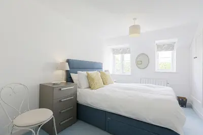 a bedroom with a blue and white bed and a chair at Sail Loft — A quiet St Mawes gem in Saint Mawes