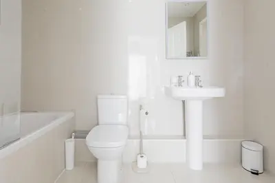 a white bathroom with a toilet and a sink at Sail Loft — A quiet St Mawes gem in Saint Mawes