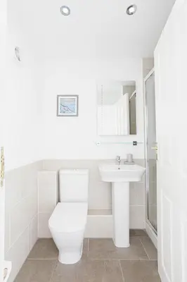 a white bathroom with a toilet and a sink at Sail Loft — A quiet St Mawes gem in Saint Mawes