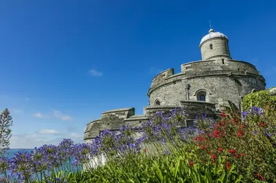 an old stone building with flowers in the foreground at Sail Loft — A quiet St Mawes gem in Saint Mawes