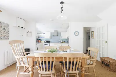 a dining room with a wooden table and chairs at Sail Loft — A quiet St Mawes gem in Saint Mawes