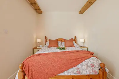 a bedroom with a wooden bed with orange pillows at Trotters barn conversion on edge of Mount Hawke in Mount Hawke