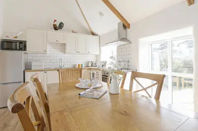 a kitchen with a wooden table and a dining room at Trotters barn conversion on edge of Mount Hawke in Mount Hawke