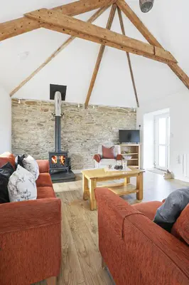 a living room with two couches and a fireplace at Trotters barn conversion on edge of Mount Hawke in Mount Hawke