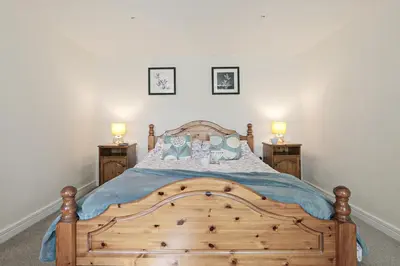 a bedroom with a wooden bed with two night stands at Trotters barn conversion on edge of Mount Hawke in Mount Hawke