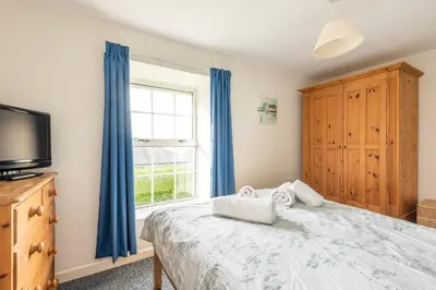 a bedroom with a bed and a tv and a window at Rosemary Cottage Edmonton set in the countryside in Wadebridge