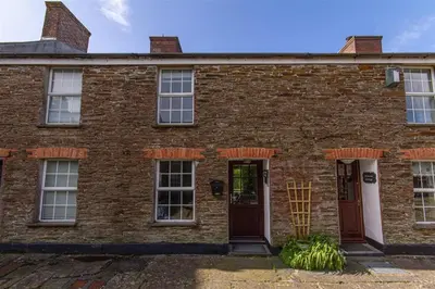 an old brick house with two doors and windows at Rosemary Cottage Edmonton set in the countryside in Wadebridge