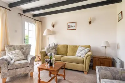 a living room with two couches and a table at Rosemary Cottage Edmonton set in the countryside in Wadebridge