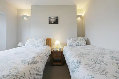 a bedroom with two beds and a table with a lamp at Well Court is a fabulous cottage with wonderful views set in the heart of Polruan village in Fowey