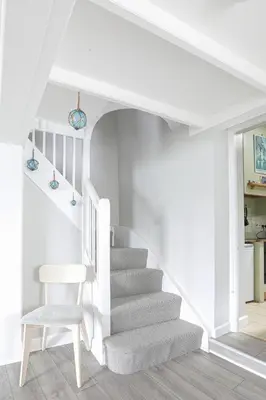 a white staircase with a chair and a table at Well Court is a fabulous cottage with wonderful views set in the heart of Polruan village in Fowey