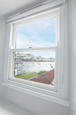 a window in a room with a view of the ocean at Well Court is a fabulous cottage with wonderful views set in the heart of Polruan village in Fowey